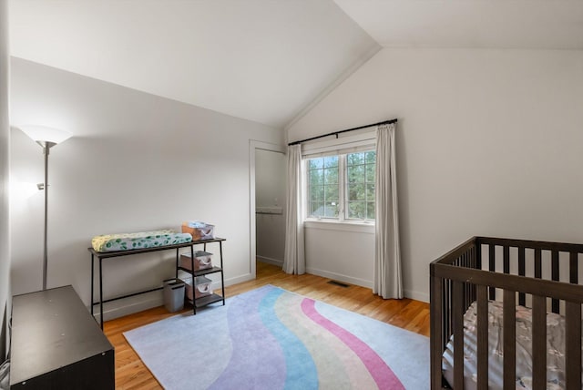 bedroom with vaulted ceiling, wood finished floors, visible vents, and baseboards