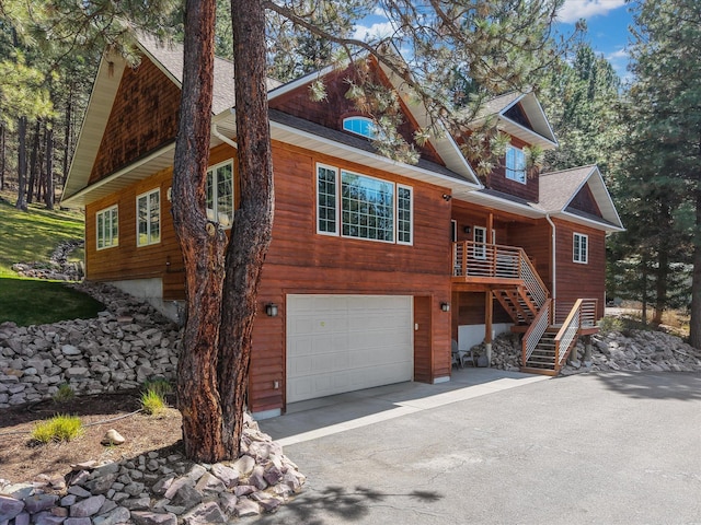 view of front of house featuring stairway, an attached garage, driveway, and roof with shingles