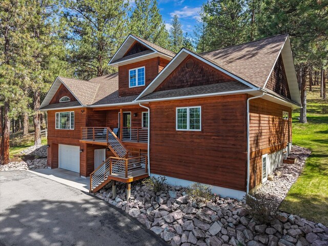 rustic home featuring an attached garage, a shingled roof, concrete driveway, and stairway