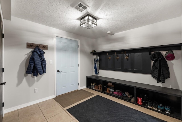 mudroom featuring baseboards, visible vents, tile patterned flooring, and a textured ceiling