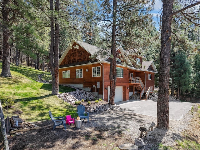 back of house with driveway, stairway, a yard, and a garage
