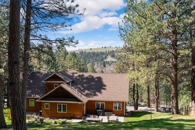 rear view of house featuring a lawn, roof with shingles, and a patio