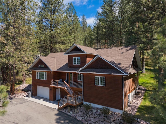 chalet / cabin featuring an attached garage, aphalt driveway, stairs, and a shingled roof