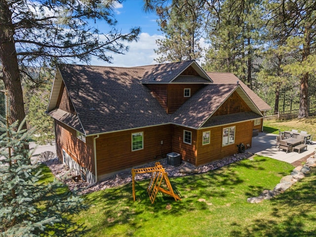 back of house featuring central air condition unit, roof with shingles, a yard, and a patio