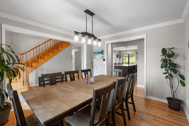 dining room with baseboards, crown molding, wood finished floors, and stairs