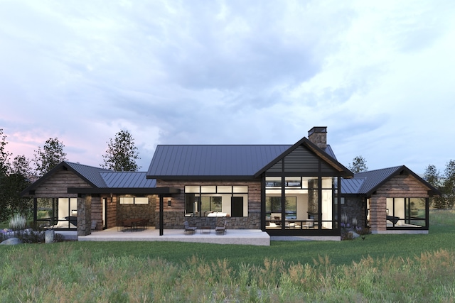 rear view of property featuring stone siding, a standing seam roof, a patio area, and metal roof