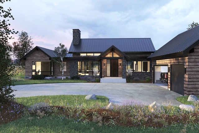 view of front of house with an attached garage, driveway, a standing seam roof, and metal roof