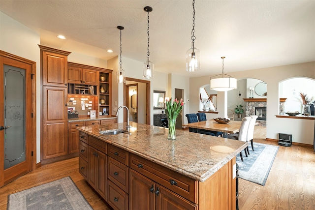 2200 Rafferty Ln, Missoula, MT 59804 - kitchen with a kitchen island with sink, light wood-style floors, pendant lighting, light stone counters, and open shelves