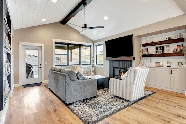 living area with recessed lighting, light wood finished floors, vaulted ceiling with beams, a glass covered fireplace, and ceiling fan
