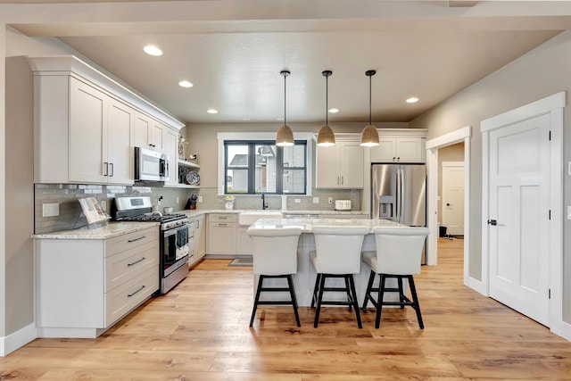7038 Max Dr, Missoula, MT 59803 - kitchen featuring stainless steel appliances, a kitchen breakfast bar, a sink, tasteful backsplash, and light wood-style floors