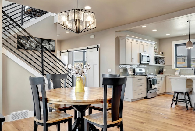 7038 Max Dr, Missoula, MT 59803 - dining area featuring a chandelier, light wood-style floors, recessed lighting, stairs, and healthy amount of natural light