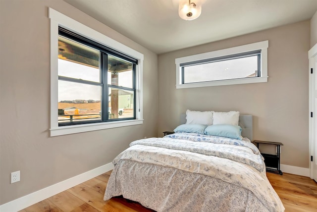 bedroom featuring light wood finished floors and baseboards