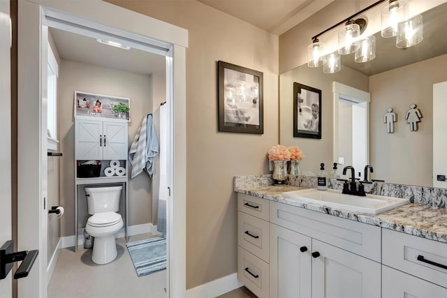 full bath with toilet, vanity, and baseboards