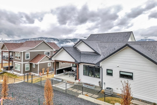 view of front facade featuring a fenced backyard, central AC unit, and a shingled roof