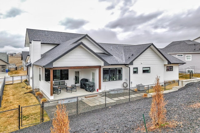7038 Max Dr, Missoula, MT 59803 - back of property with a shingled roof, outdoor lounge area, a gate, a fenced backyard, and a patio