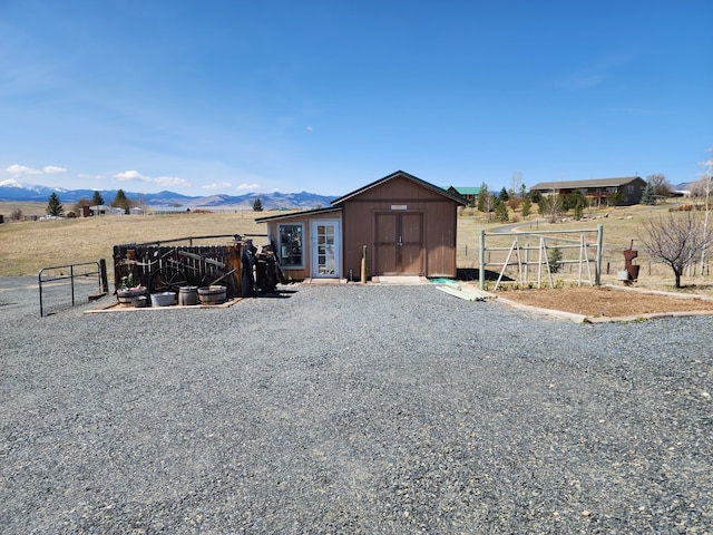view of shed with fence, a gate, and a mountain view