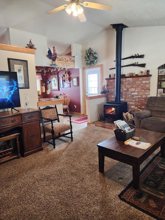 carpeted living room featuring a wood stove, a ceiling fan, and vaulted ceiling