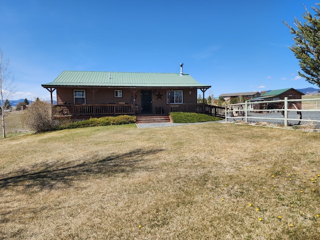back of house featuring metal roof, fence, a yard, and covered porch