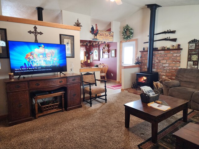 carpeted living area featuring baseboards, a wood stove, ceiling fan, and lofted ceiling