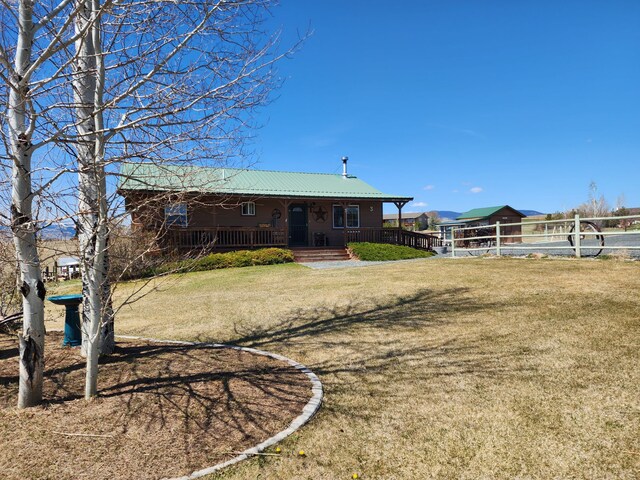 rear view of property featuring covered porch, a yard, and metal roof