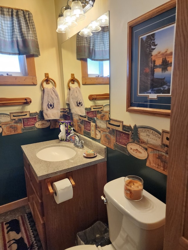 bathroom featuring vanity, a notable chandelier, a wealth of natural light, and toilet