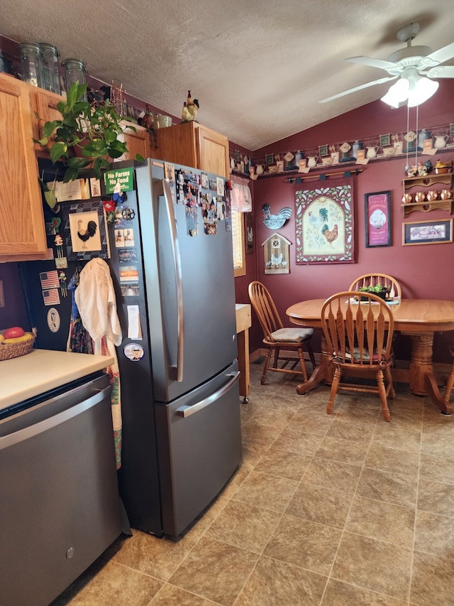 kitchen featuring ceiling fan, a textured ceiling, vaulted ceiling, dishwasher, and freestanding refrigerator