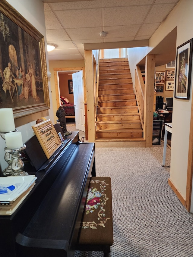 interior space with carpet flooring, a paneled ceiling, and stairway