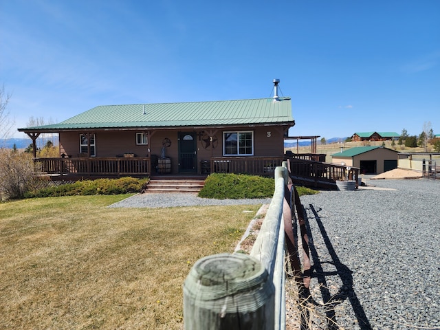 view of front facade featuring fence, metal roof, a porch, and a front lawn
