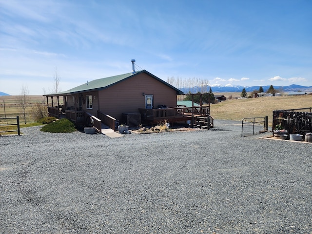 view of side of property featuring fence, a wooden deck, and cooling unit