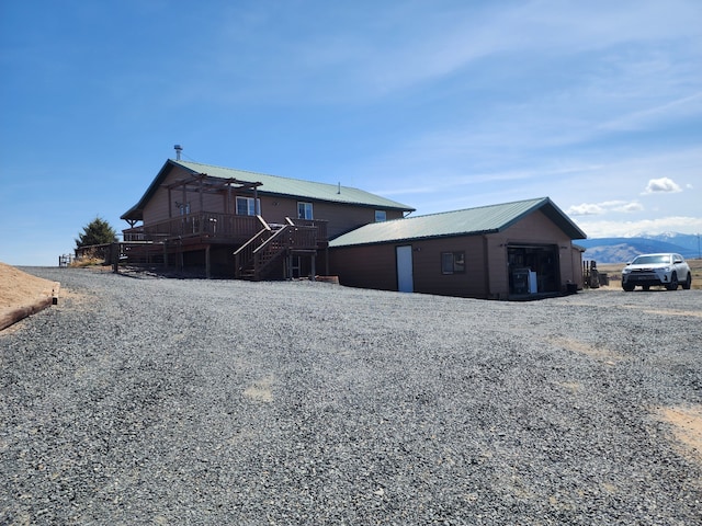 rear view of property featuring stairs, an outdoor structure, a deck, and metal roof