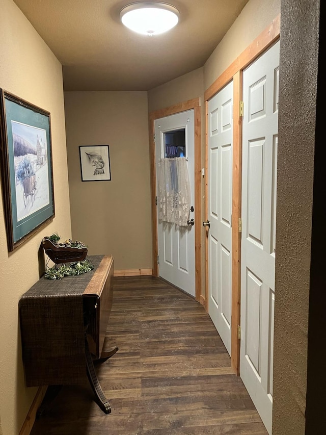 doorway featuring baseboards and dark wood-type flooring
