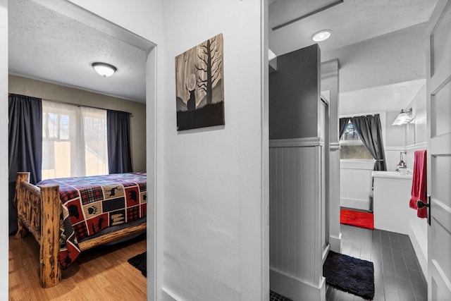 interior space with a wainscoted wall, wood finished floors, a wealth of natural light, and a textured ceiling