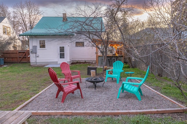playground at dusk featuring a fire pit, a yard, and fence