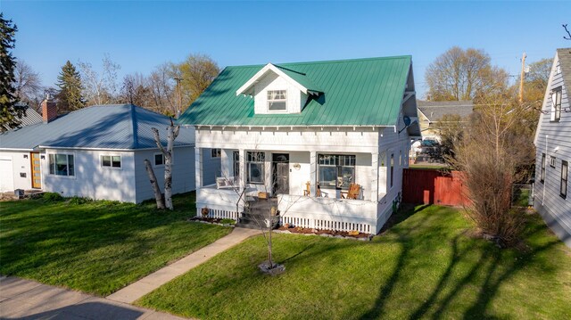 view of front of house with fence, a front lawn, and metal roof