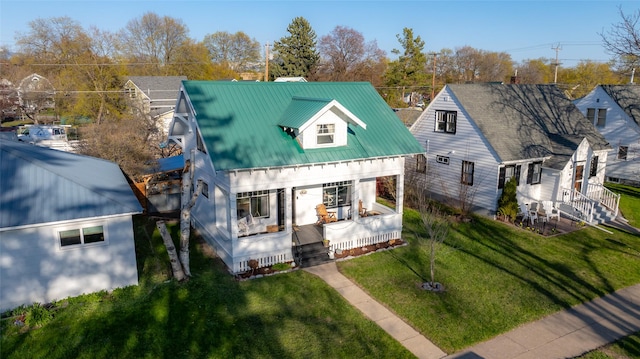 view of front facade with covered porch, a front yard, and metal roof