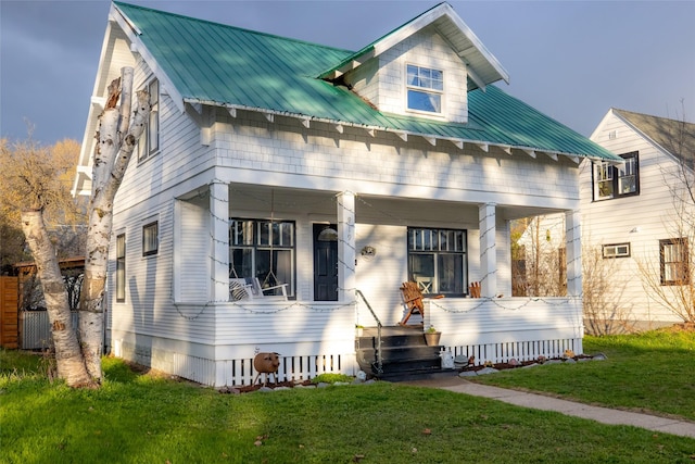 view of front facade with a front lawn, metal roof, and covered porch