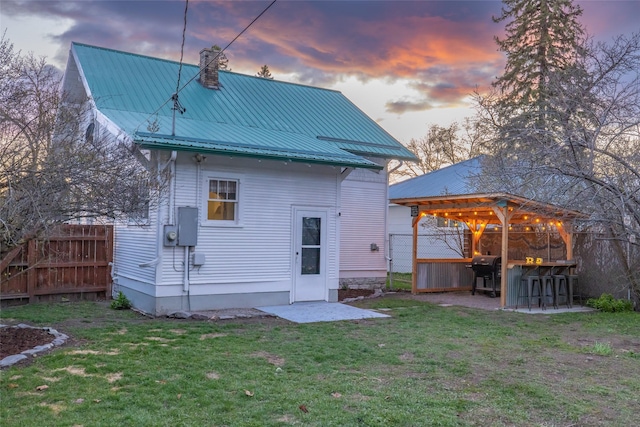 back of property with a gazebo, a lawn, a chimney, and fence
