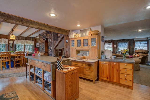 kitchen featuring dark countertops, light wood-style flooring, open floor plan, and lofted ceiling with beams