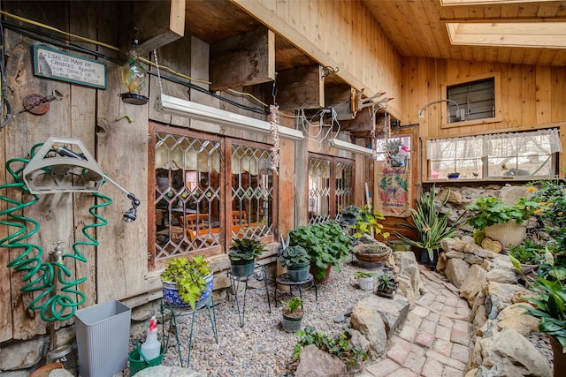 interior space featuring wooden walls, lofted ceiling, wooden ceiling, and brick floor