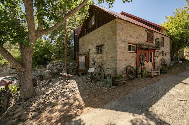 view of side of property with stone siding and stairs