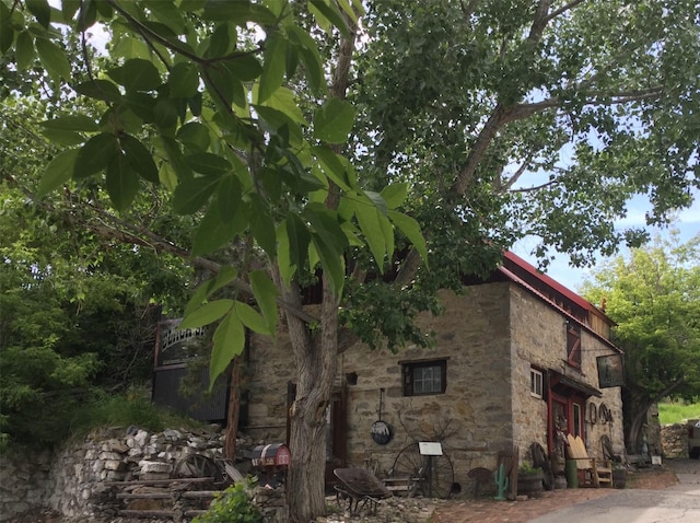 exterior space featuring stone siding and metal roof