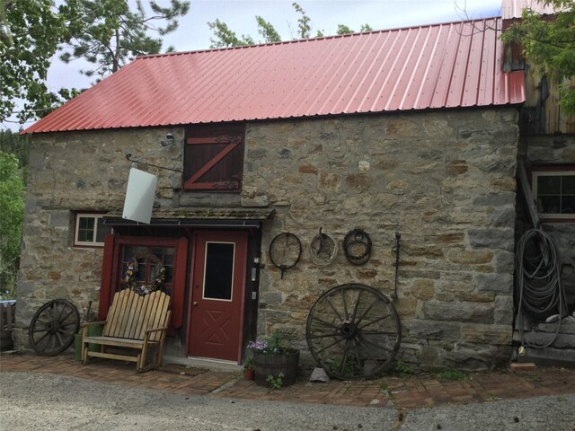 view of front of property featuring stone siding and metal roof