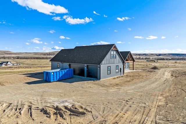exterior space with a shingled roof, board and batten siding, driveway, an outbuilding, and a garage