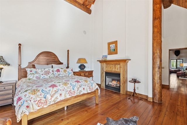 231 Arrowhead Dr, Whitefish, MT 59937 - bedroom featuring high vaulted ceiling, beam ceiling, hardwood / wood-style floors, and a glass covered fireplace