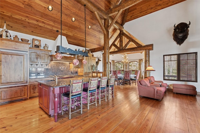 231 Arrowhead Dr, Whitefish, MT 59937 - kitchen with high vaulted ceiling, a kitchen breakfast bar, tasteful backsplash, beamed ceiling, and a chandelier