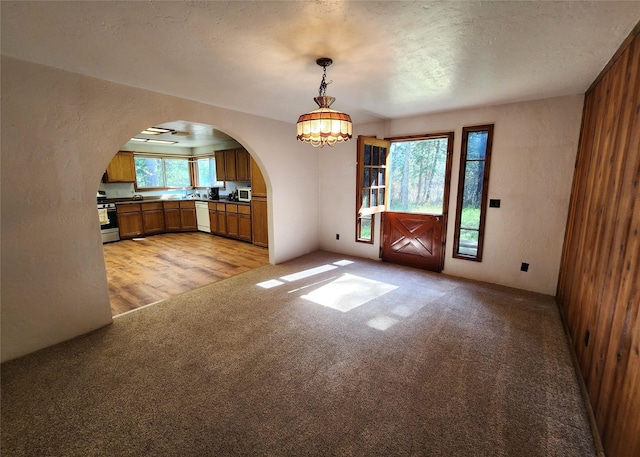 unfurnished dining area featuring arched walkways, light carpet, and an inviting chandelier