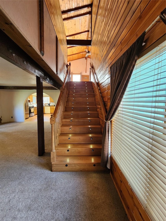 stairway with wooden ceiling, carpet flooring, and arched walkways