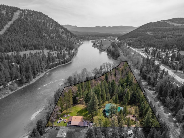 drone / aerial view with a water and mountain view and a forest view