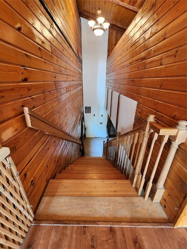 stairs featuring visible vents, wood finished floors, and wood walls