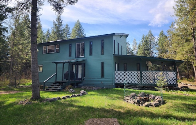 rear view of house featuring a lawn and a fire pit
